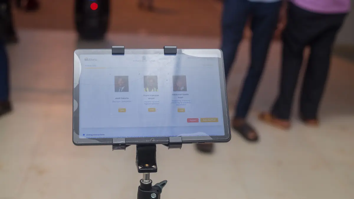Abato electronic ballot screen with voters in the background